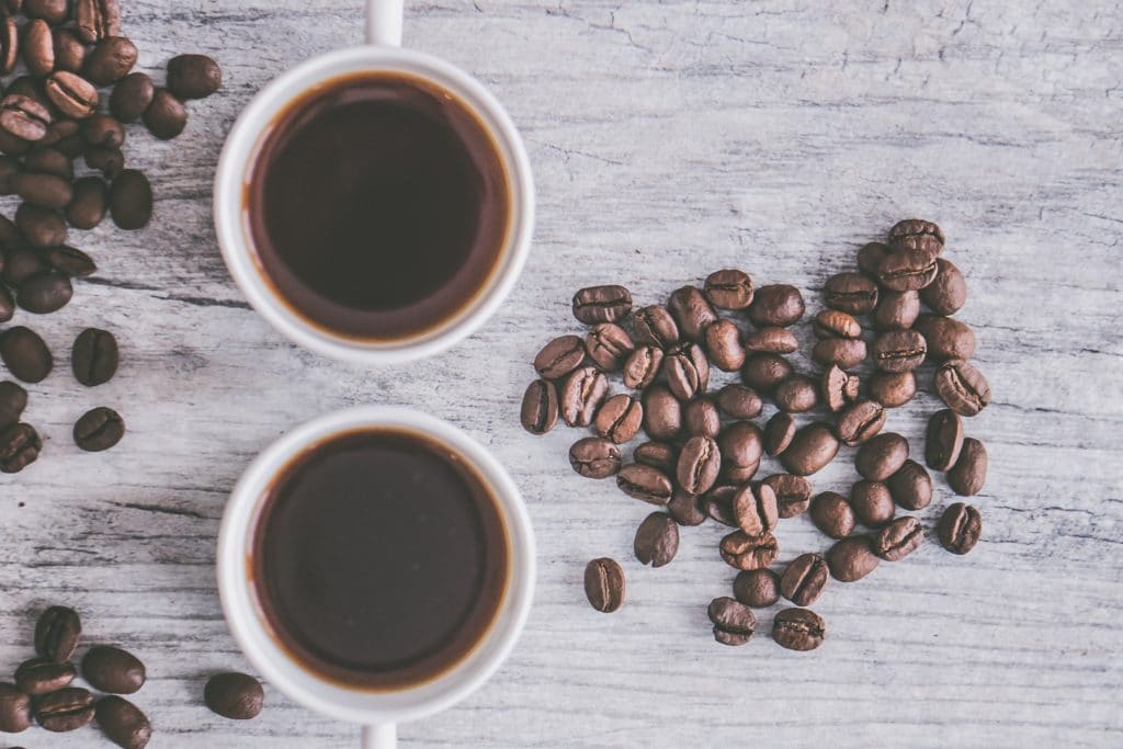 Two coffee cups and coffee beans on a table