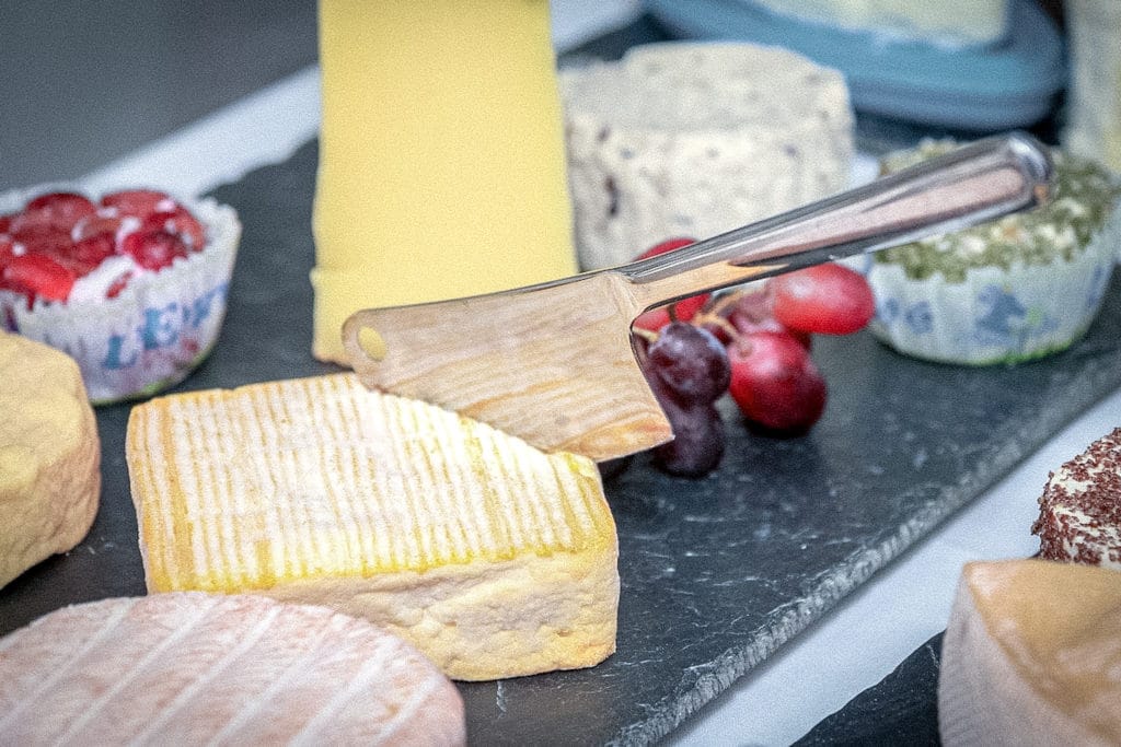 Cheese plate on a silver platter with different cheeses and red grapes