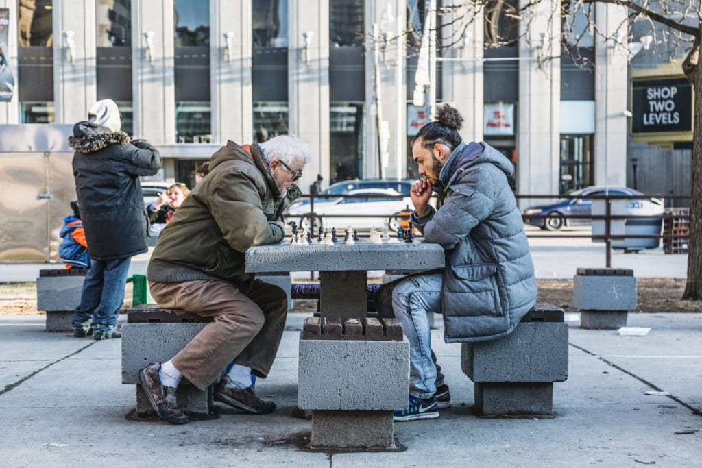 Two men playing chess at a table on the street