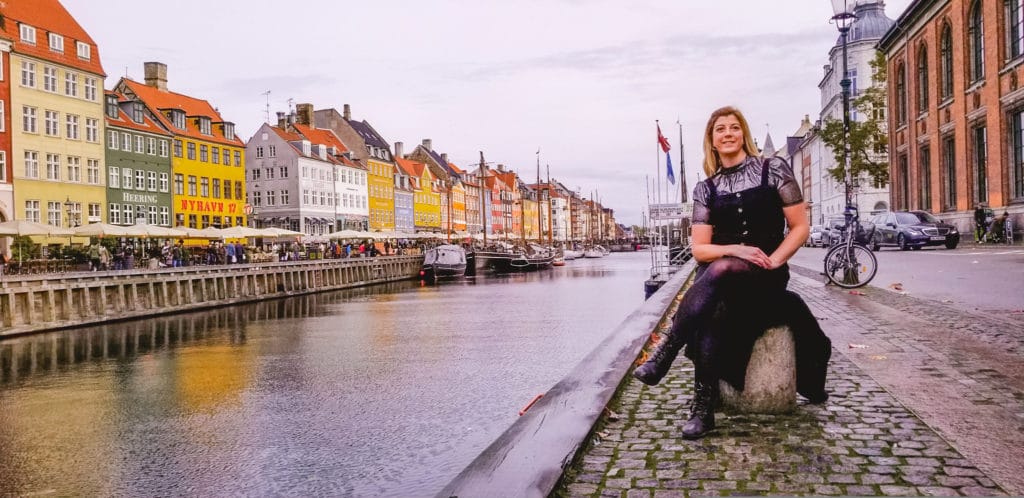 Eden sitting in front of the colorful buildings at Nyhavn in Copenhagen