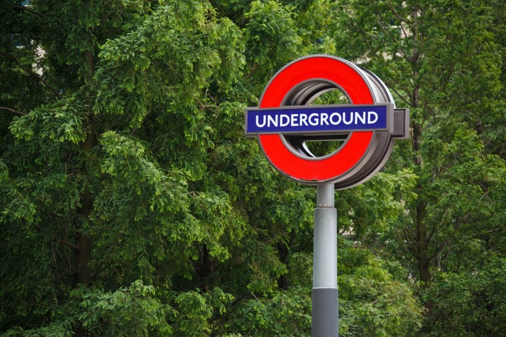 London Underground sign in front of leafy green trees