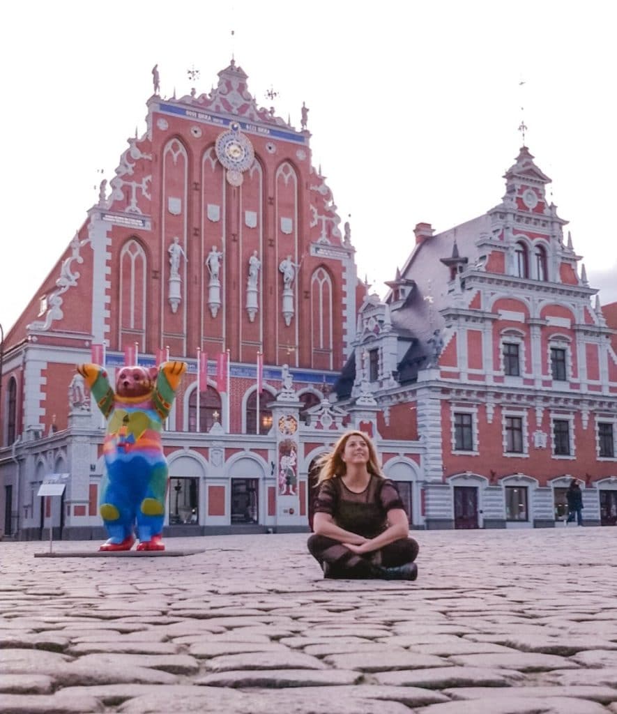 Eden Fite sitting on the ground in front of House of the Black Heads in Riga, Latvia